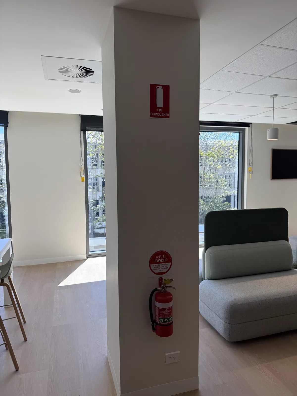 Wall-mounted fire extinguisher and identification signs on a column in a modern common area
